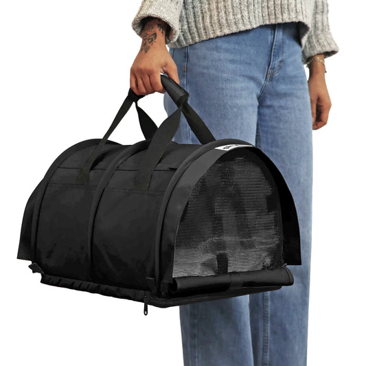 Person holding a black SturdiBag Pro 3.0 soft-sided pet carrier with mesh panels and top handles.