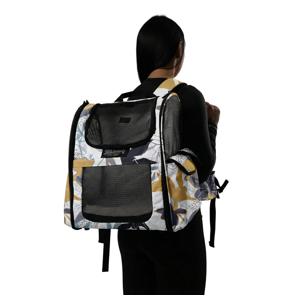 Woman wearing a Sturdi Everyday Pet Backpack with a limited edition floral print in gold, blue, and white.