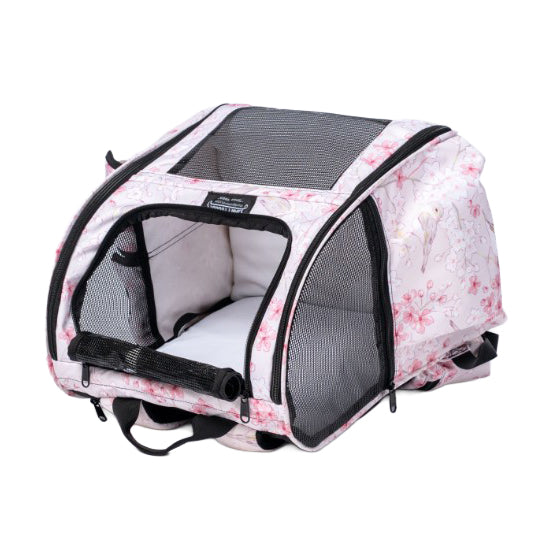 Pink pet backpack with cherry blossom print, mesh windows, and an open front flap showing a white interior pad.