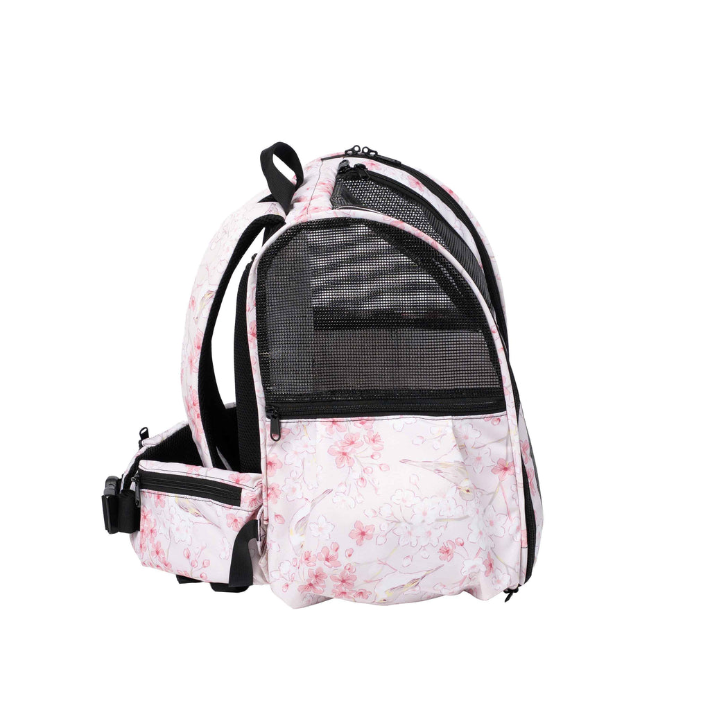 Pink pet backpack with a delicate floral print, black mesh panels, and adjustable straps.