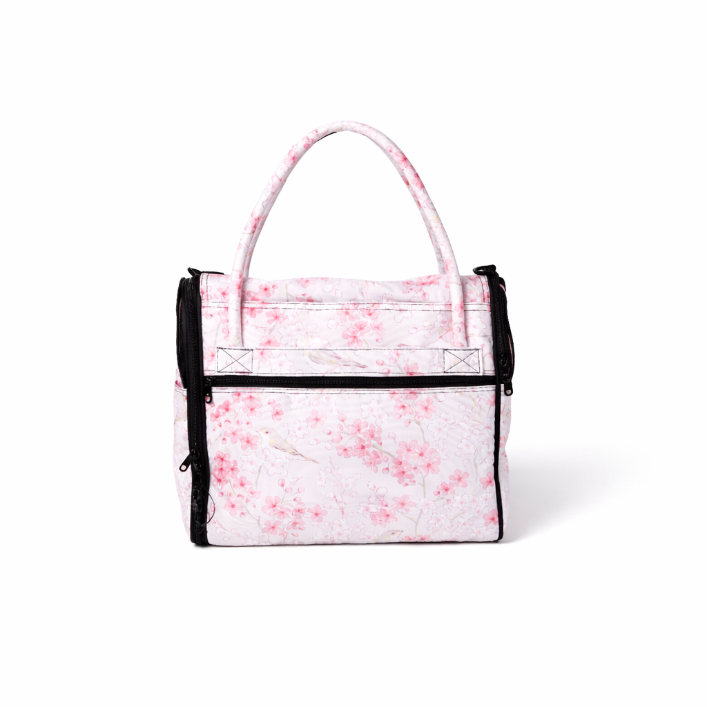 Incognito discreet pet travel tote with a light pink cherry blossom and bird pattern, black zippers, and handles.