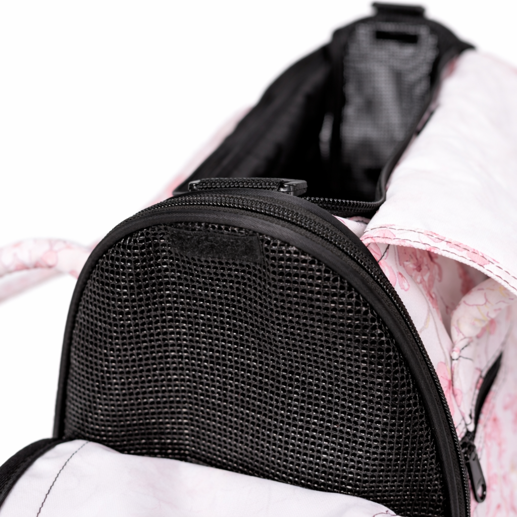 Close-up of a white and pink patterned Incognito pet travel tote with black mesh window and zipper.
