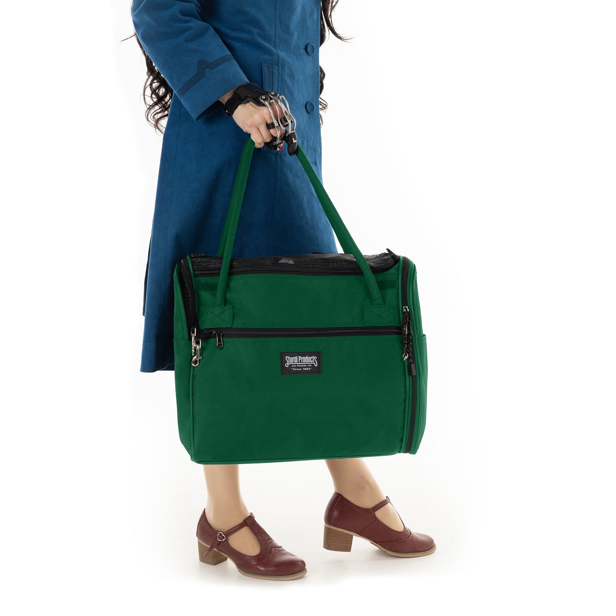 Person holding a green Incognito discreet pet travel tote with black accents and mesh panels.