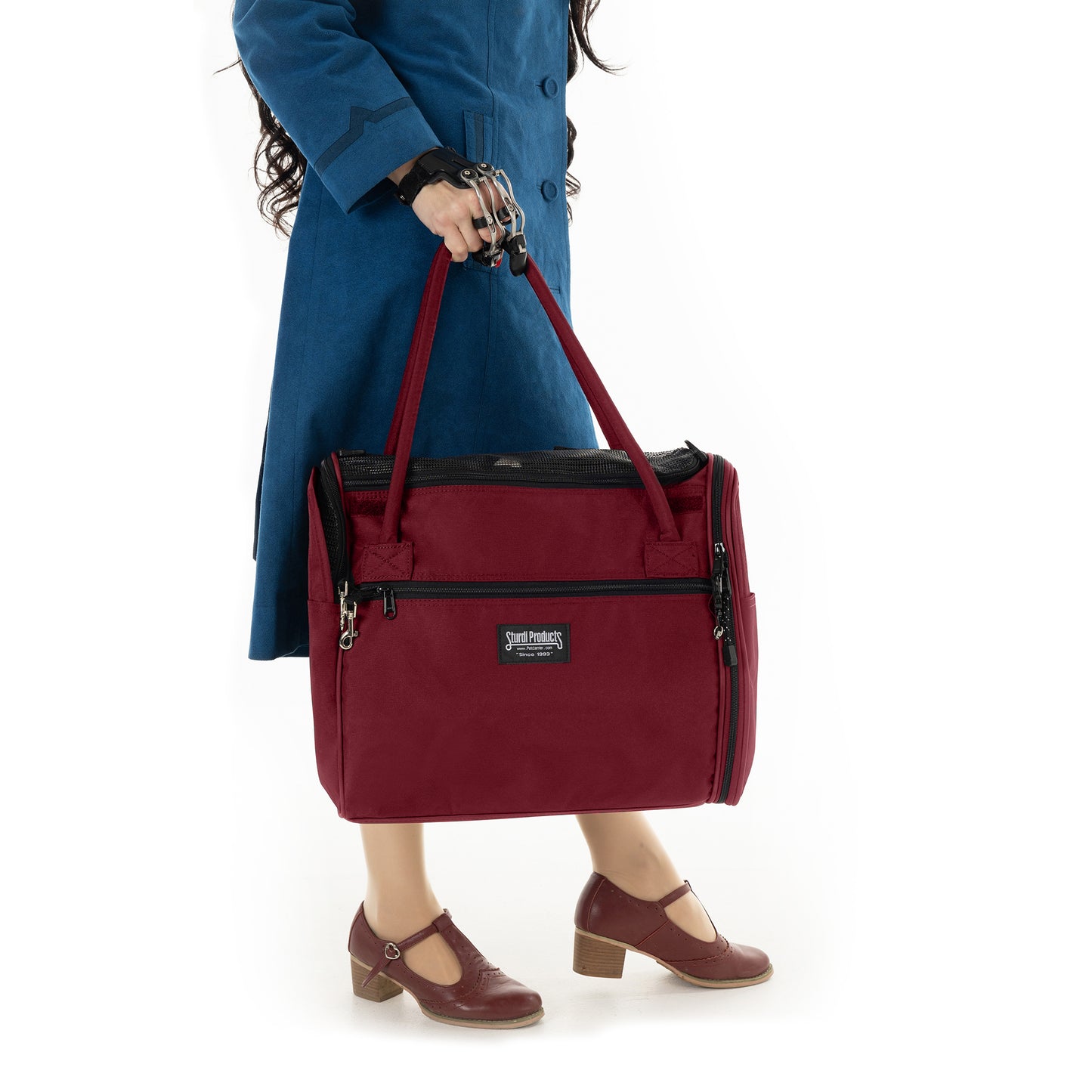 Person in blue coat holding a burgundy Sturdi Products Incognito discreet pet travel tote.