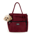 Small dog peeking from a dark red Incognito discreet pet travel tote with black zippers and shoulder strap.