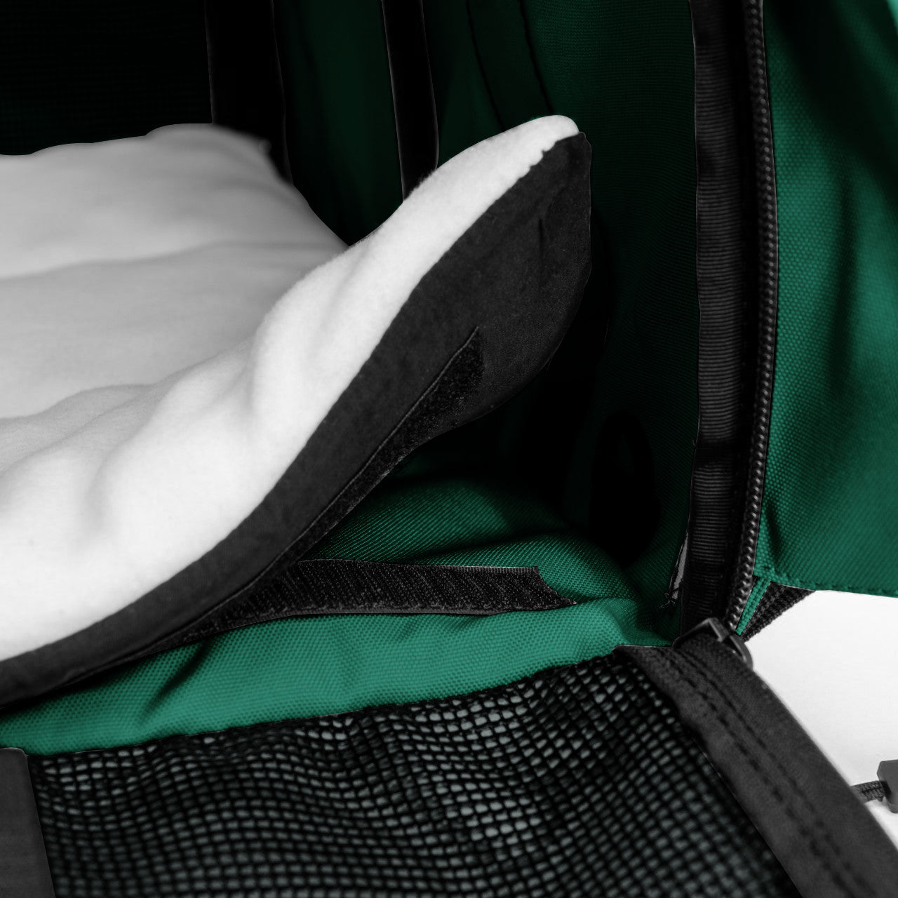 White fleece comfort pad with black trim inside a green SturdiBag pet carrier.
