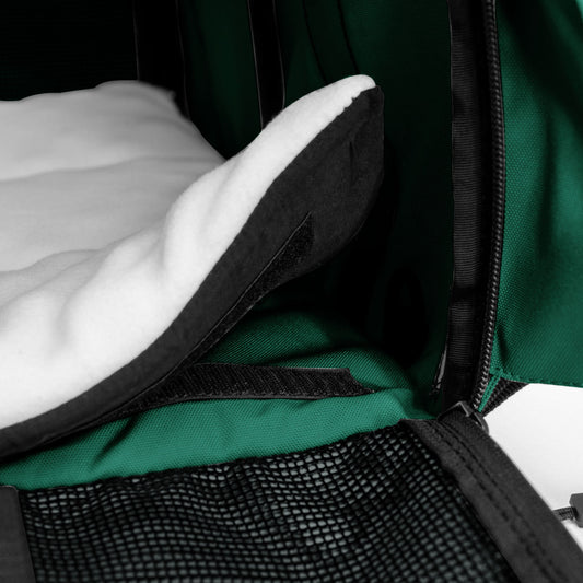 White fleece comfort pad with black trim inside a green SturdiBag pet carrier.