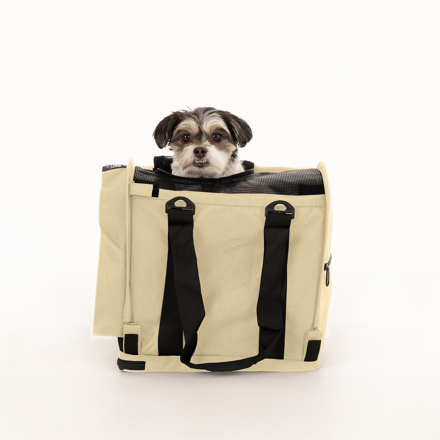 Small dog in a tan SturdiBag Pro 2.0 soft-sided pet carrier with black straps and mesh top.