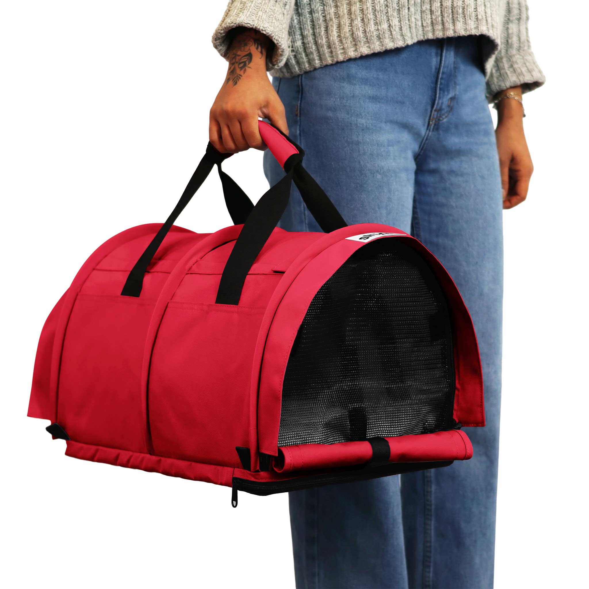 Person holding a red SturdiBag Pro 3.0 divided pet carrier with black mesh panels and handles.
