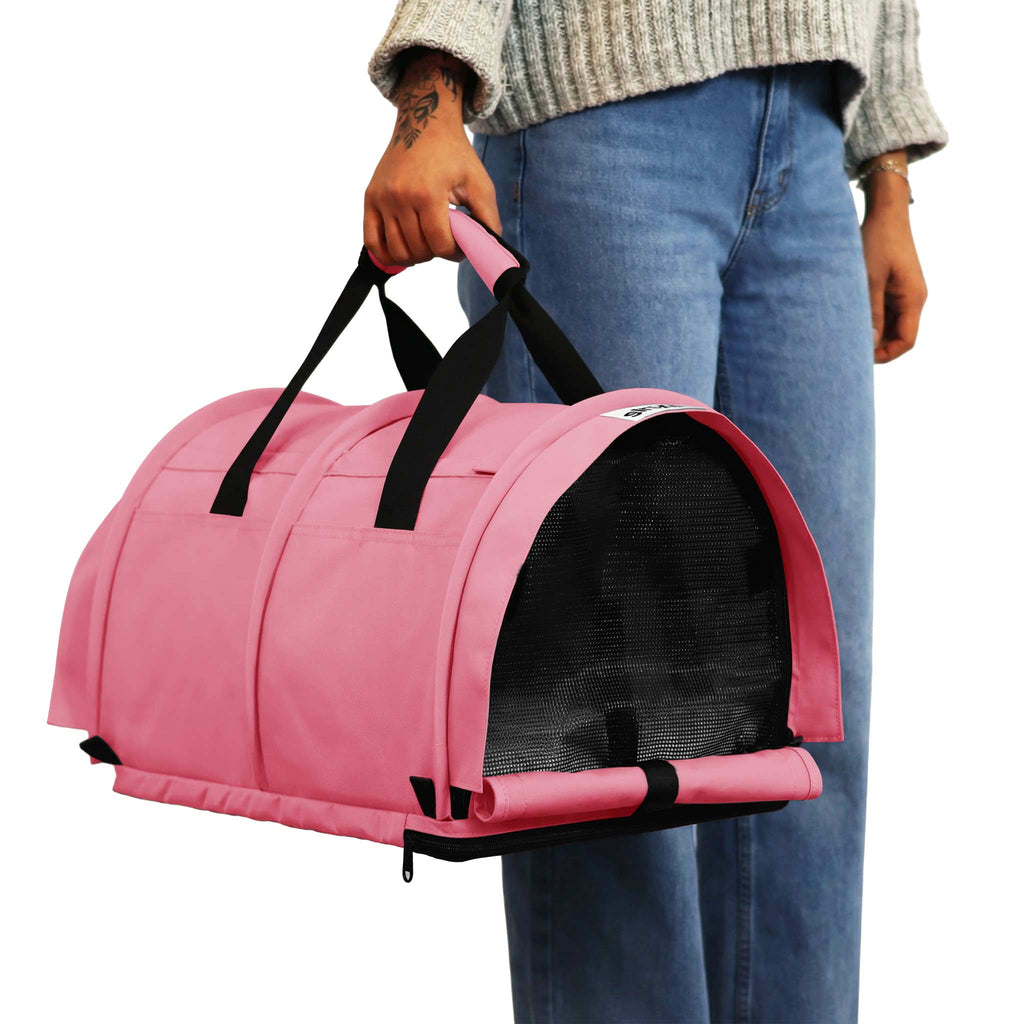 Pink SturdiBag Pro 3.0 divided pet carrier with black mesh windows and handles, held by a person.
