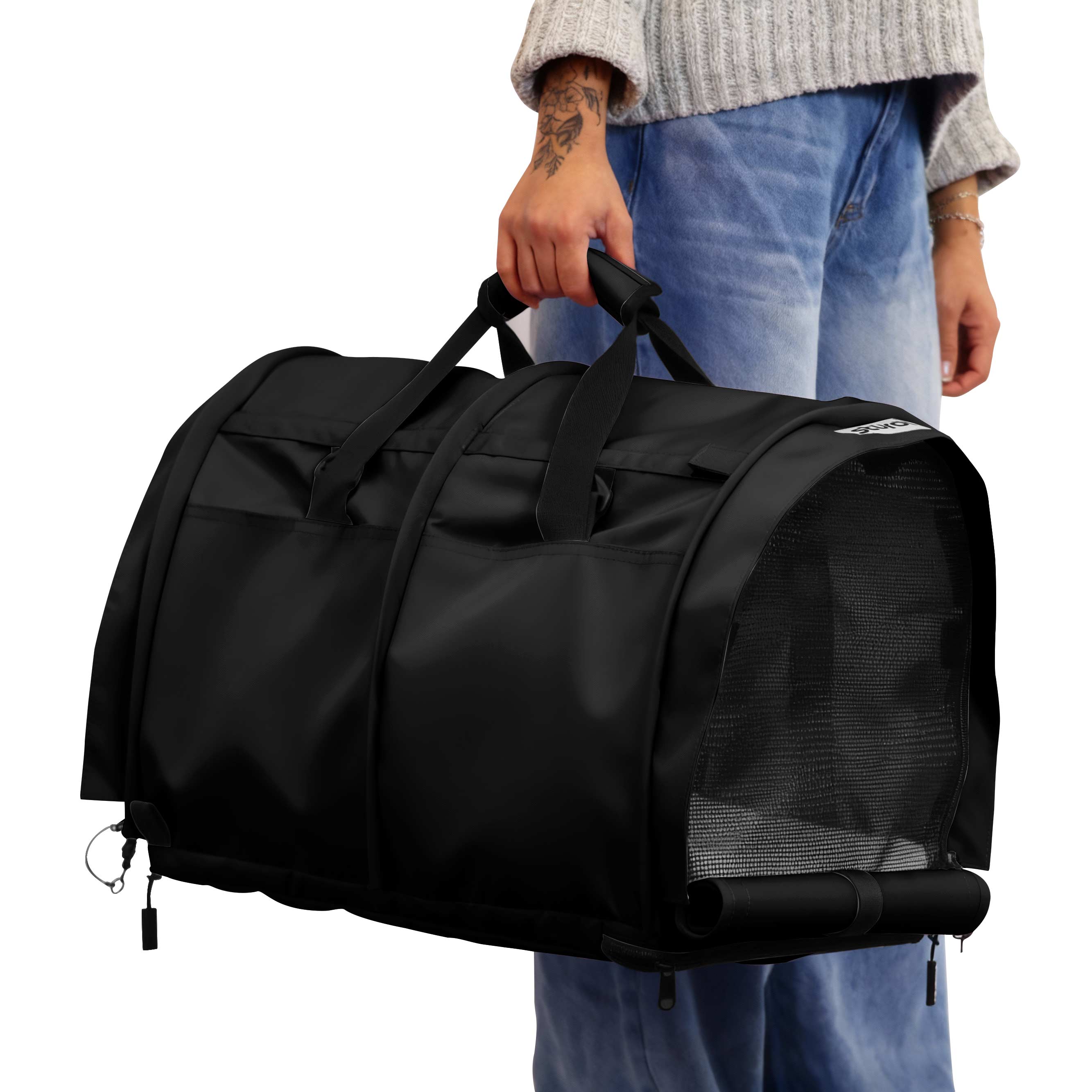 Person holding a black SturdiBag Pro 3.0 divided pet carrier with mesh panels and top handles.