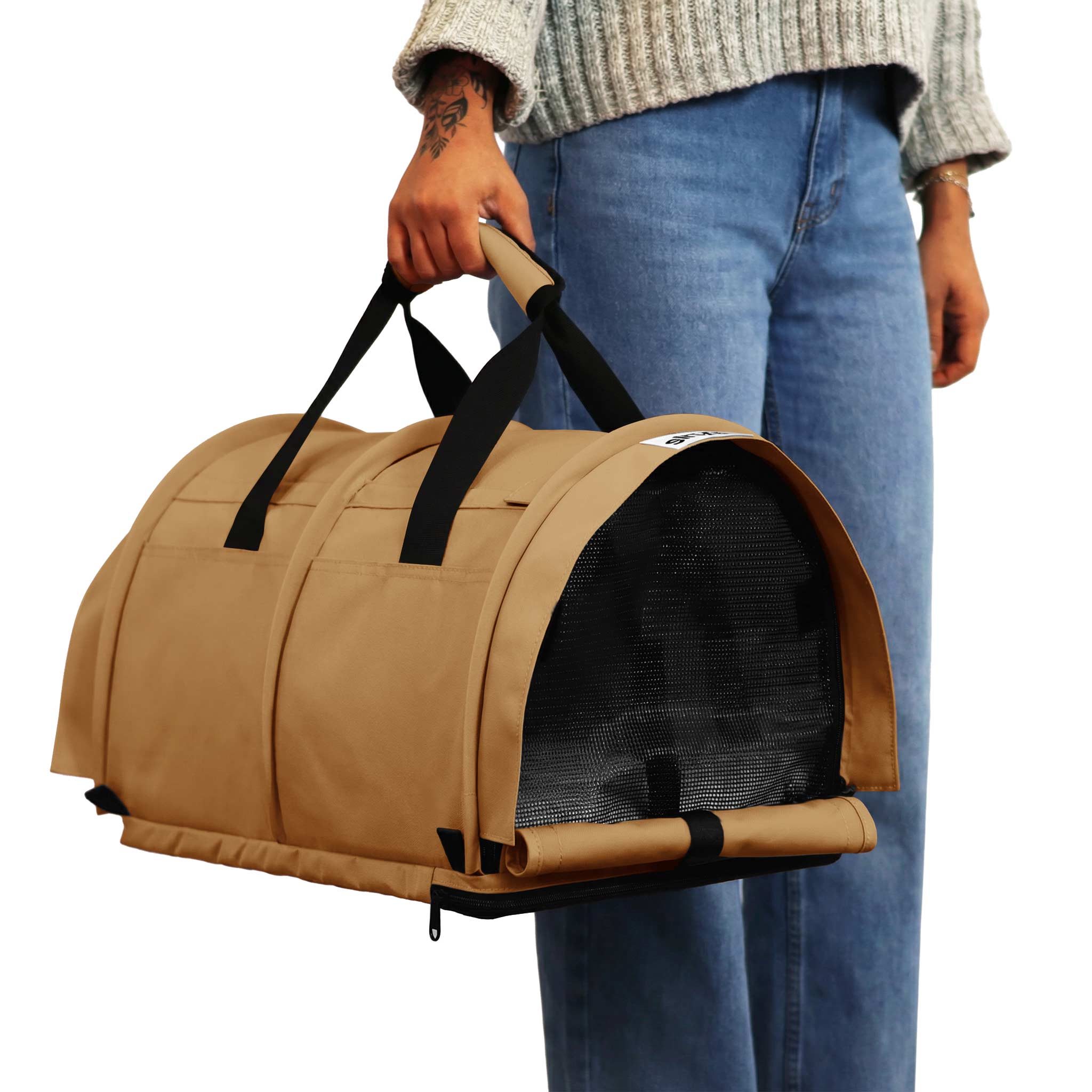 Person holding a tan SturdiBag Pro 3.0 divided pet carrier with black mesh and straps.