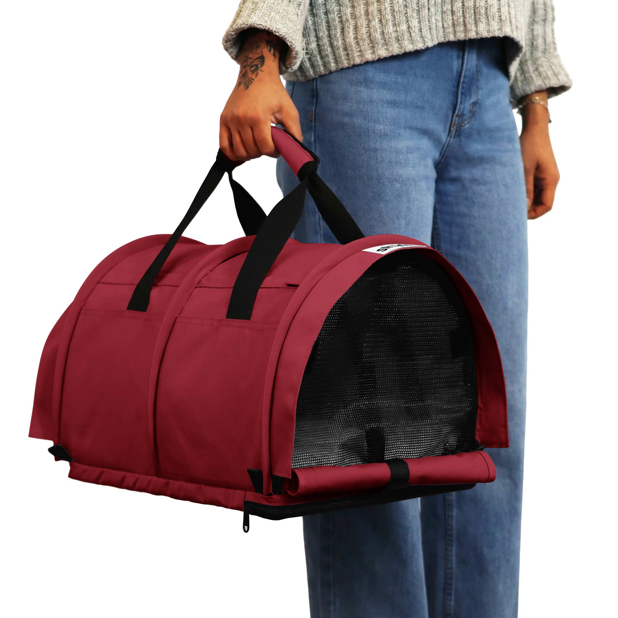 Person holding a red SturdiBag Pro 3.0 soft-sided pet carrier with mesh window and black handles.