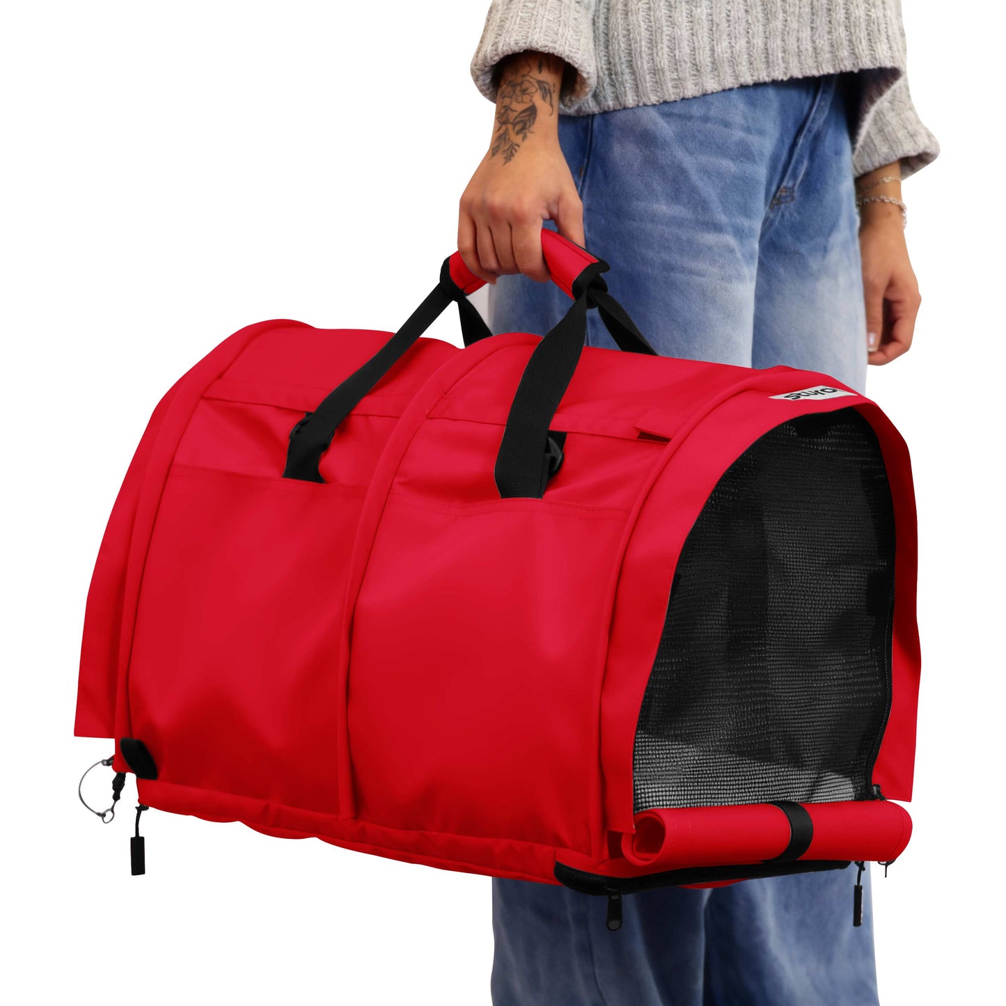 Person holding a red SturdiBag Pro 3.0 soft-sided pet carrier with mesh window and black straps.