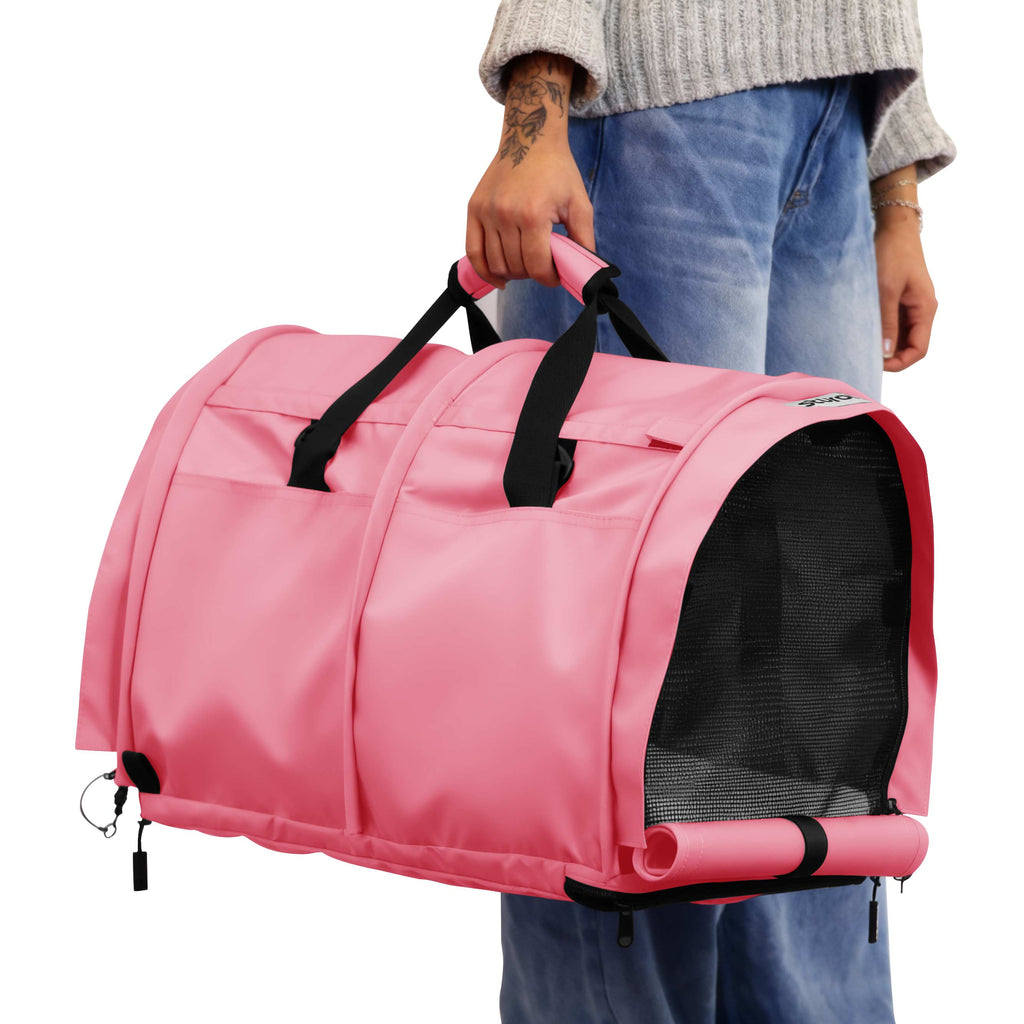 Person holding a pink SturdiBag Pro 3.0 soft-sided pet carrier with black mesh and handles.