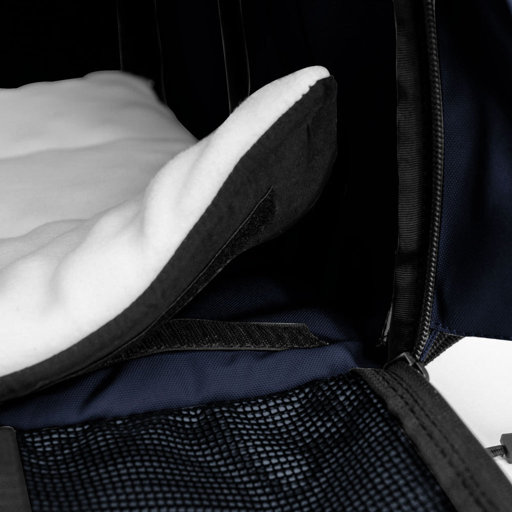 Close-up of a navy SturdiBag Pro 3.0 pet carrier with a white fleece pad and black mesh panel.