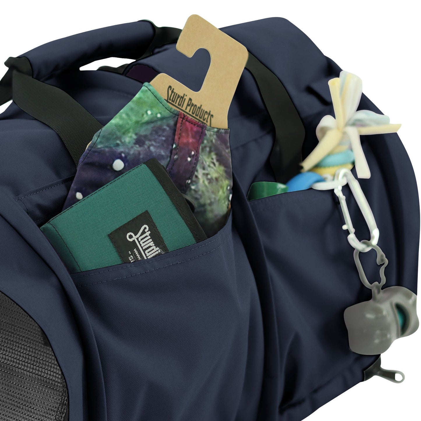 Navy SturdiBag Pro 3.0 pet carrier with side pockets holding a wallet, mask, and pet toy.