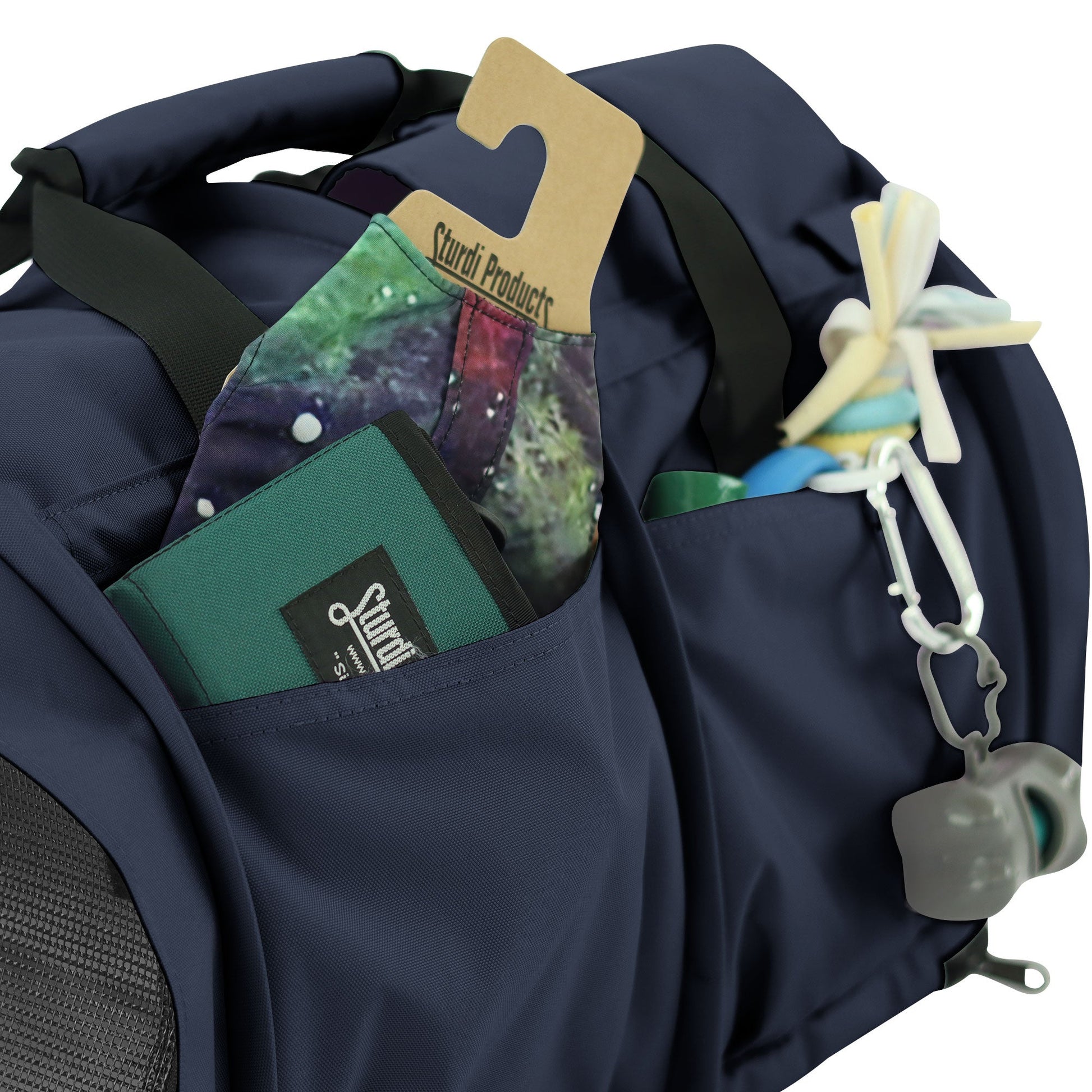 Navy SturdiBag Pro 3.0 pet carrier with side pockets holding a wallet, mask, and pet toy.