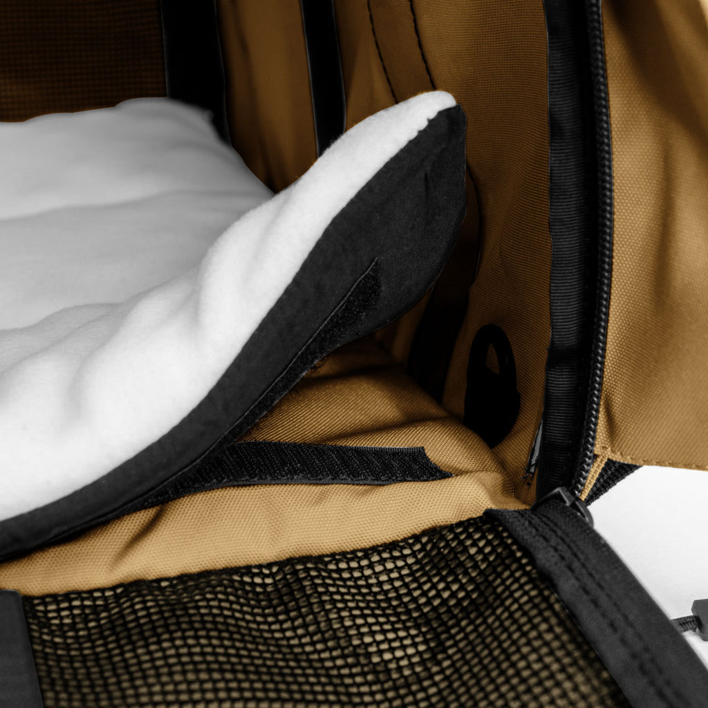 Close-up of a tan SturdiBag Pro 3.0 pet carrier interior with a white fleece pad and mesh window.