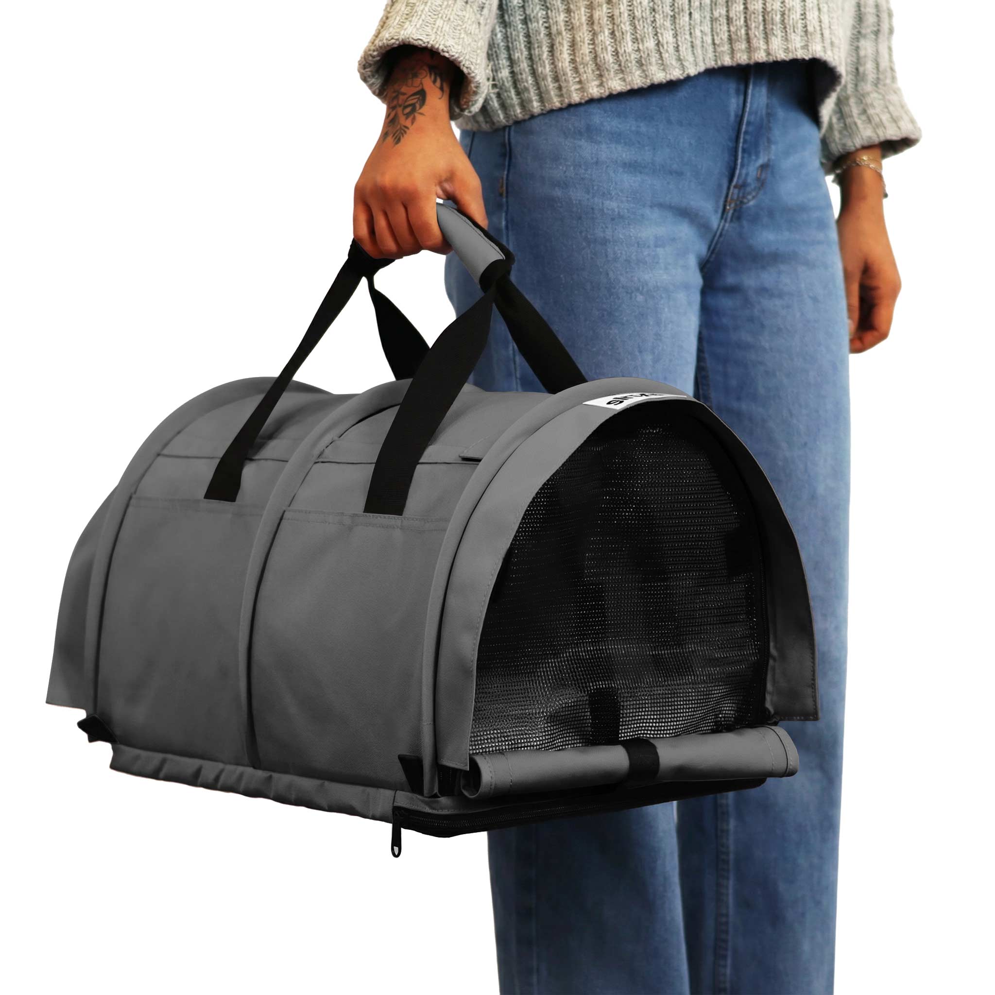 Person holding a grey SturdiBag Pro 3.0 soft-sided pet carrier with mesh panels and black straps.