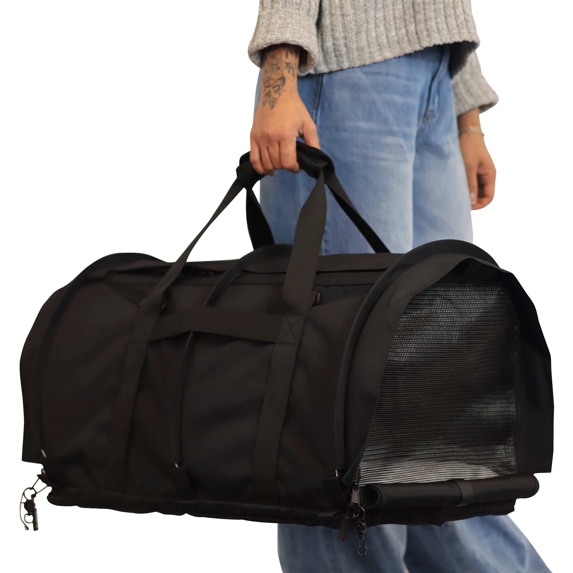 Person holding a black SturdiBag Pro 3.0 soft-sided pet carrier with mesh panels and handles.