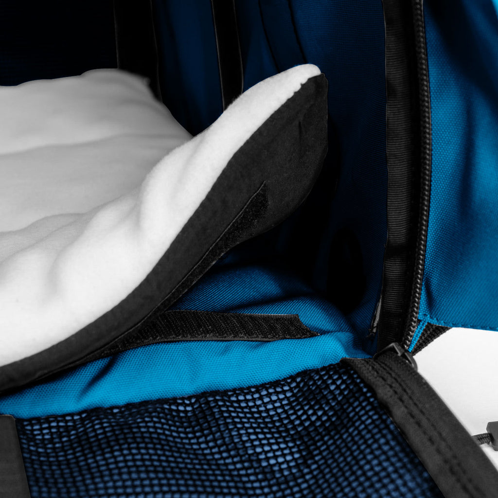 Close-up of a blue SturdiBag Pro 3.0 pet carrier interior with a white fleece comfort pad and mesh pocket.