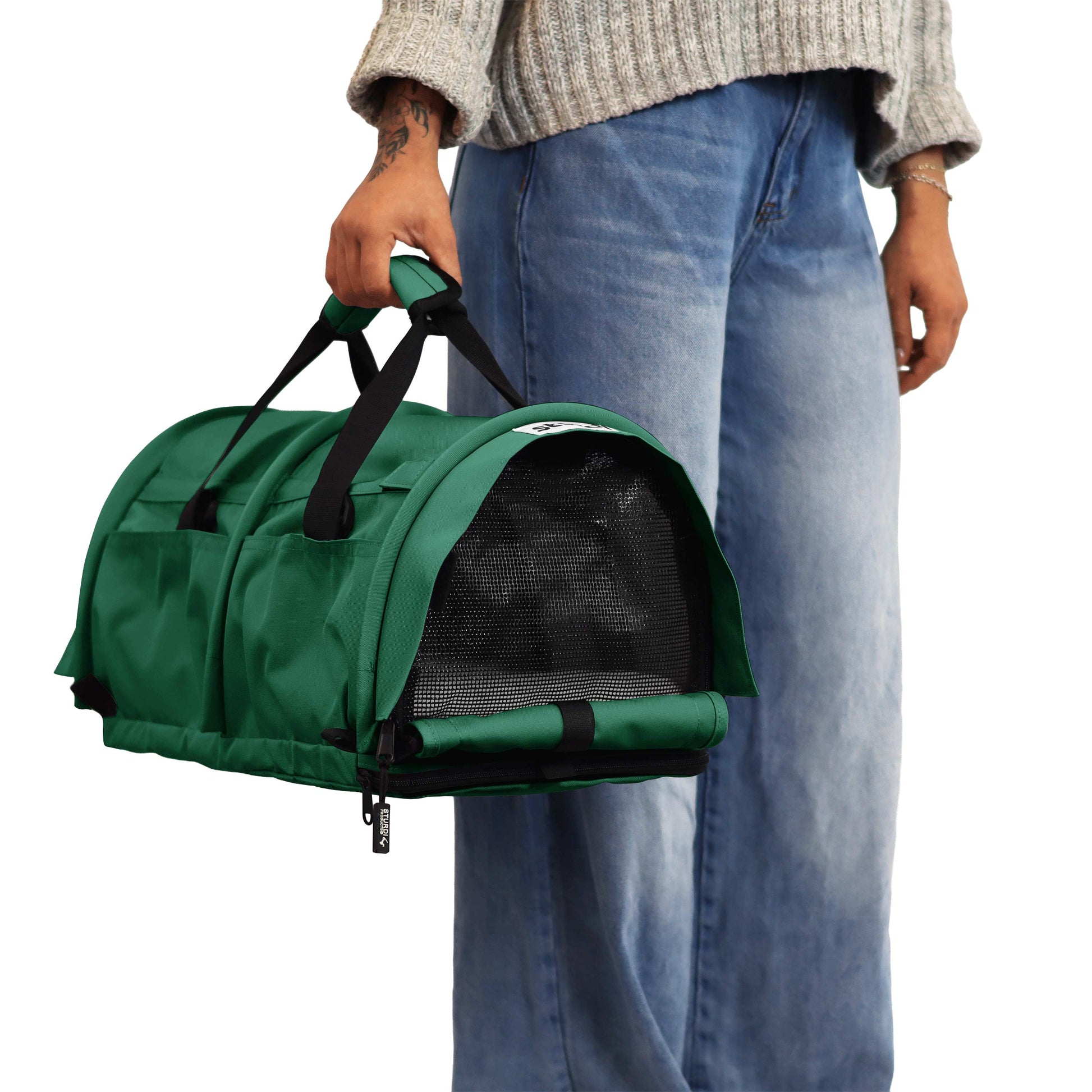 Person holding a green SturdiBag Pro 3.0 soft-sided pet carrier with mesh window and black straps.