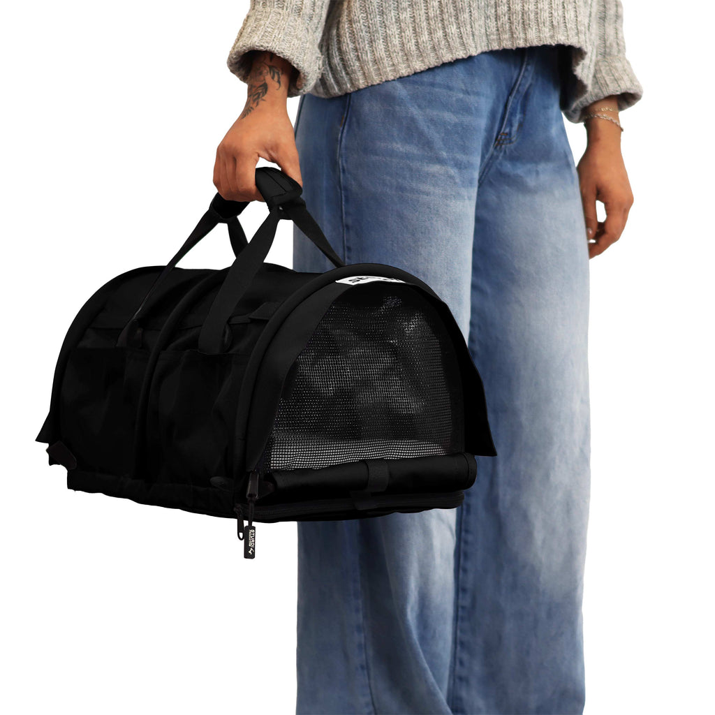 Person holding a black SturdiBag Pro 3.0 soft-sided pet carrier with mesh panels.