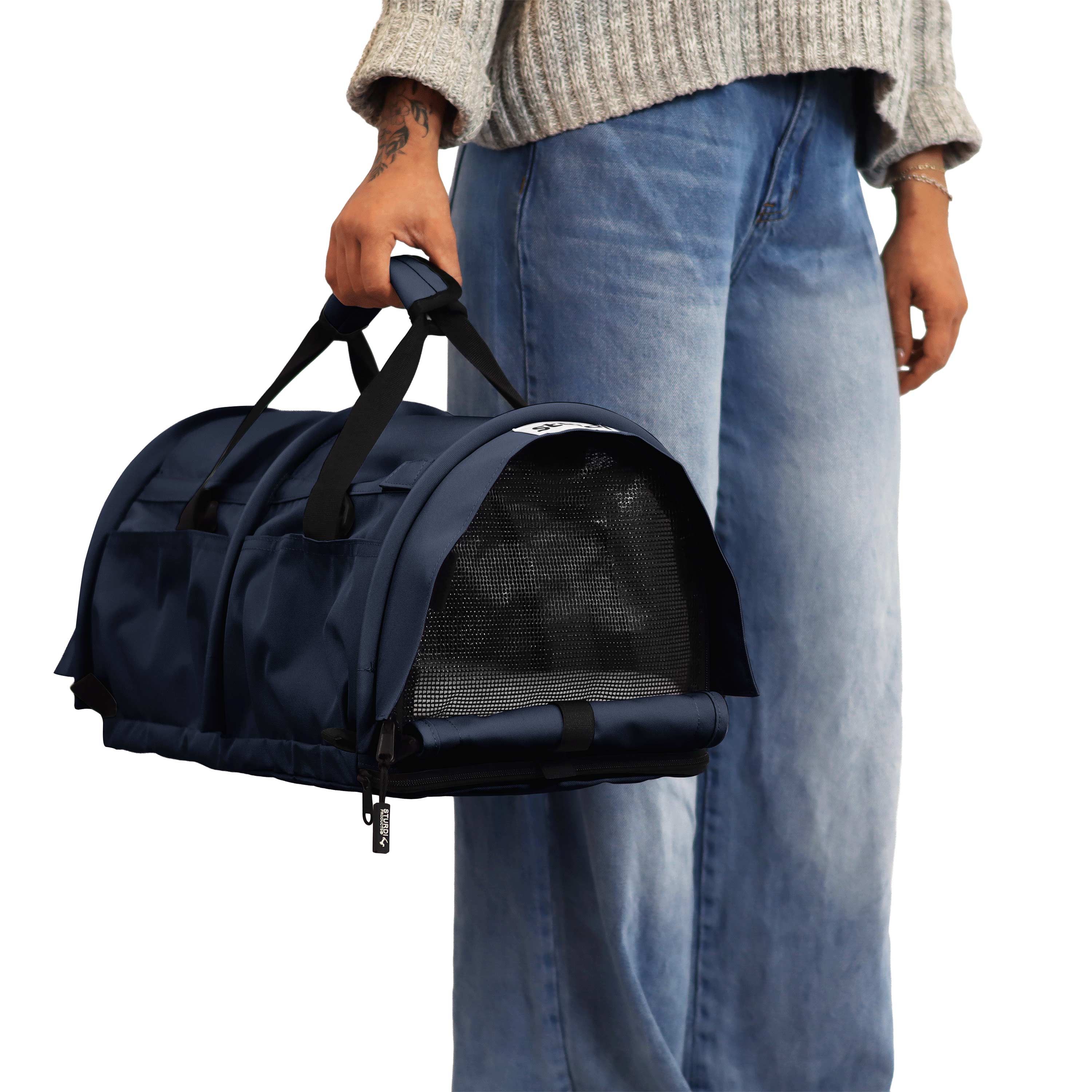 Person holding a navy blue SturdiBag Pro 3.0 soft-sided pet carrier with mesh window.