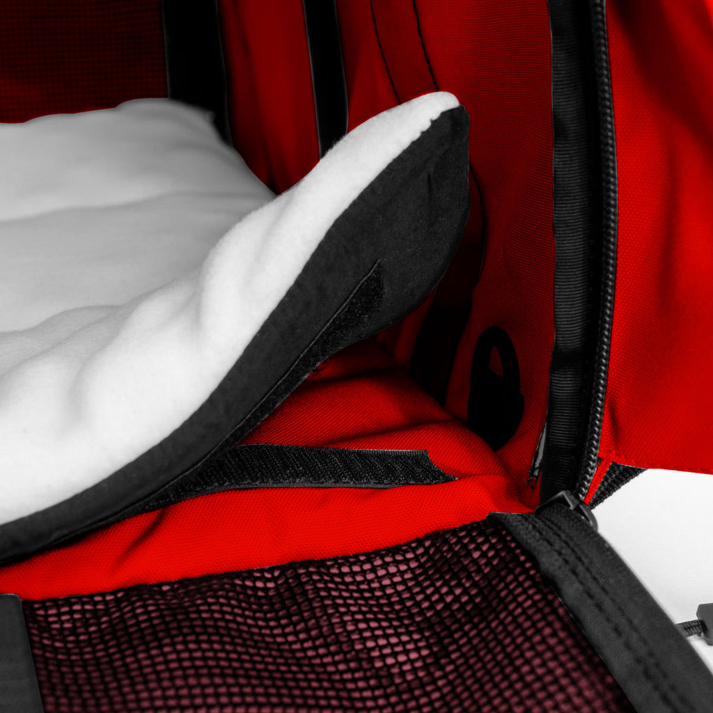 Close-up of a red SturdiBag Pro 3.0 pet carrier with a white fleece pad and black mesh.