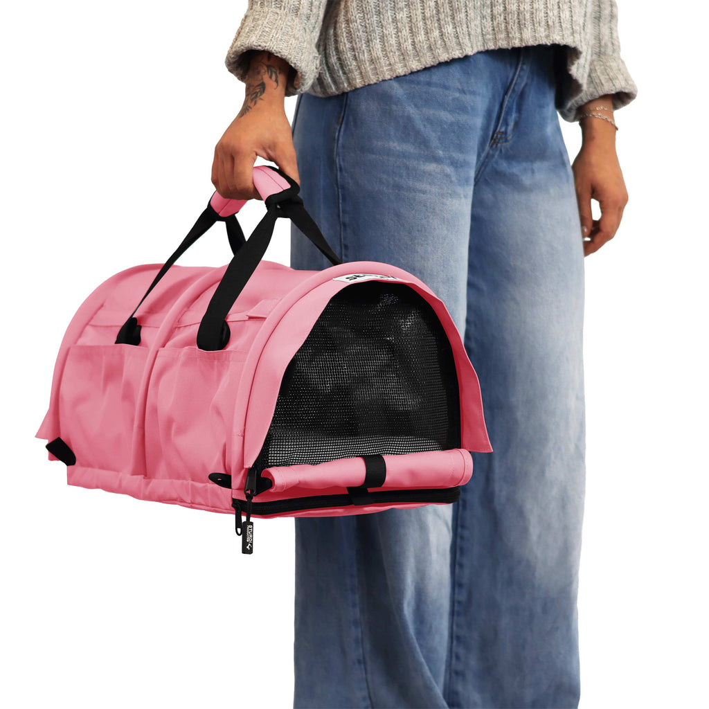 Person holding a pink SturdiBag Pro 3.0 soft-sided pet carrier with mesh window and black straps.