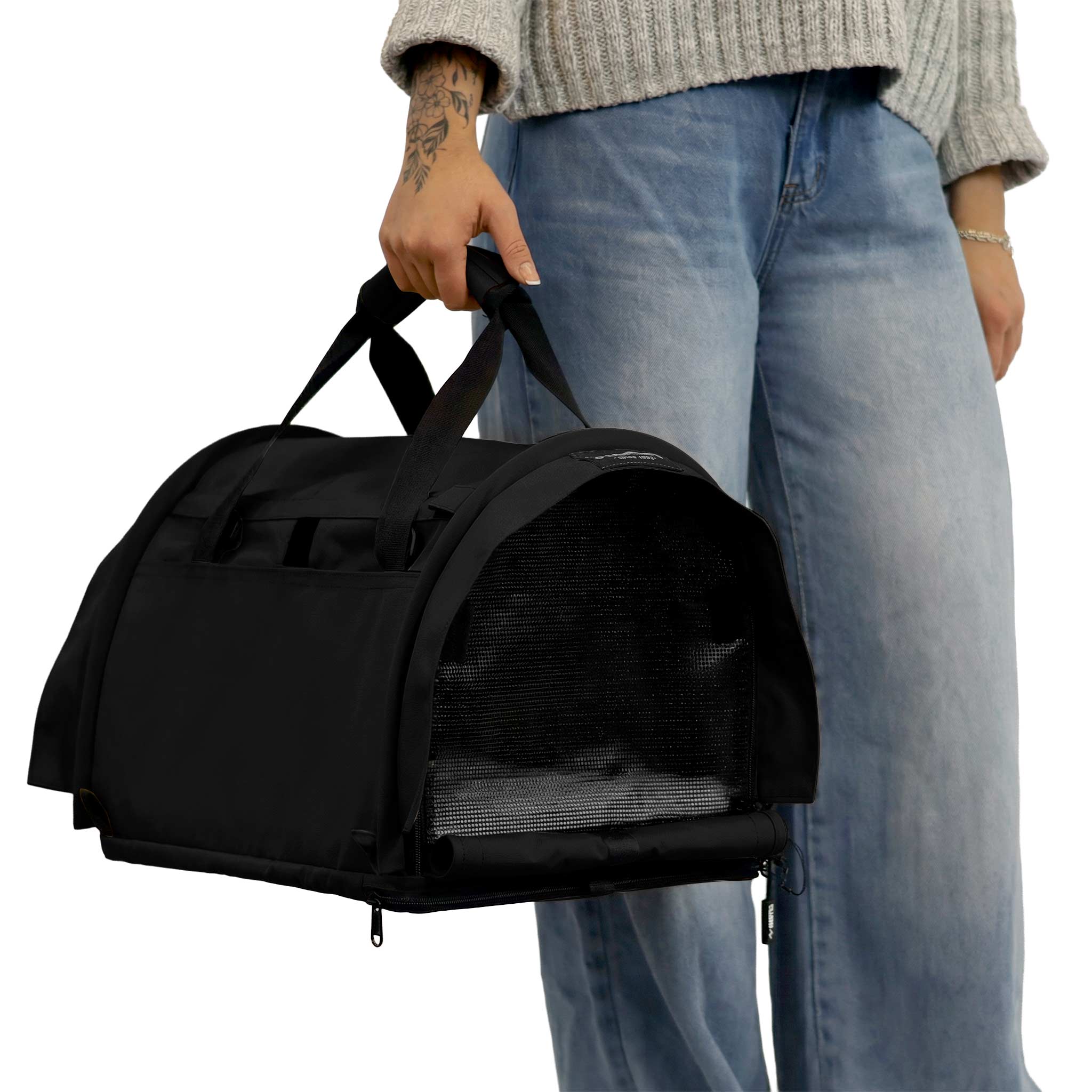 Person holding a black SturdiBag Pro 3.0 soft-sided pet carrier with mesh panels and top handle.