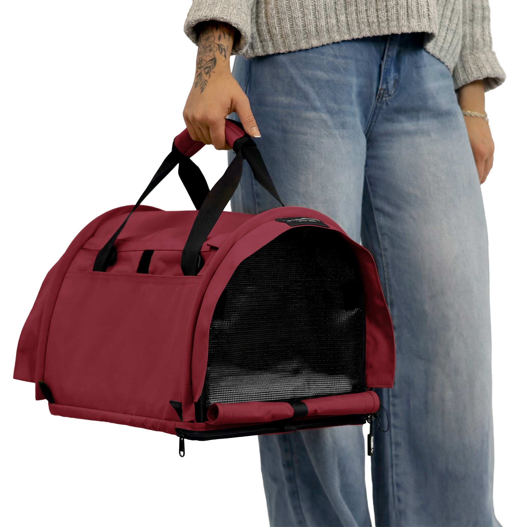 Person holding a red SturdiBag Pro 3.0 soft-sided pet carrier with mesh window and black straps.