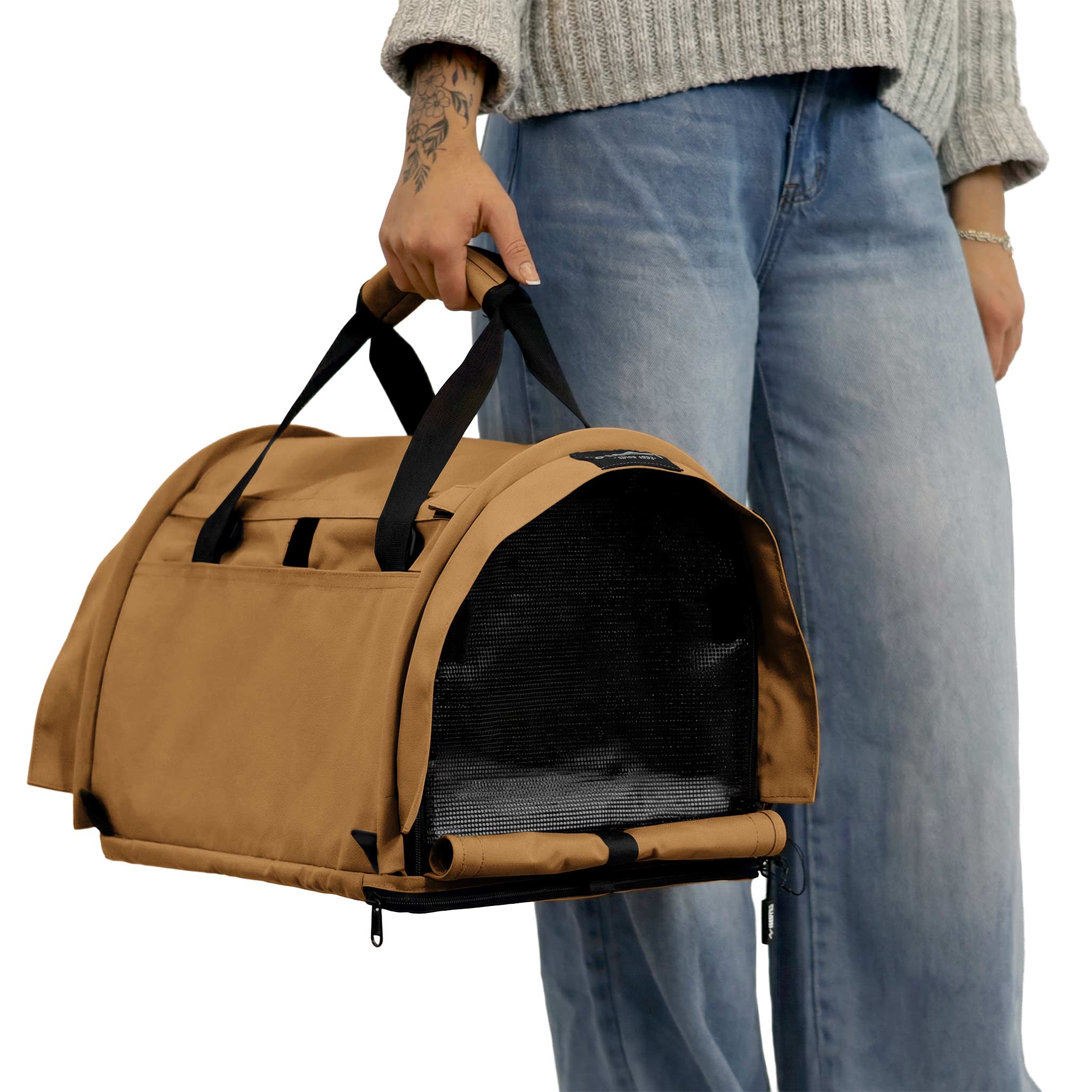 Person holding a tan SturdiBag Pro 3.0 soft-sided pet carrier with black mesh window and handles.