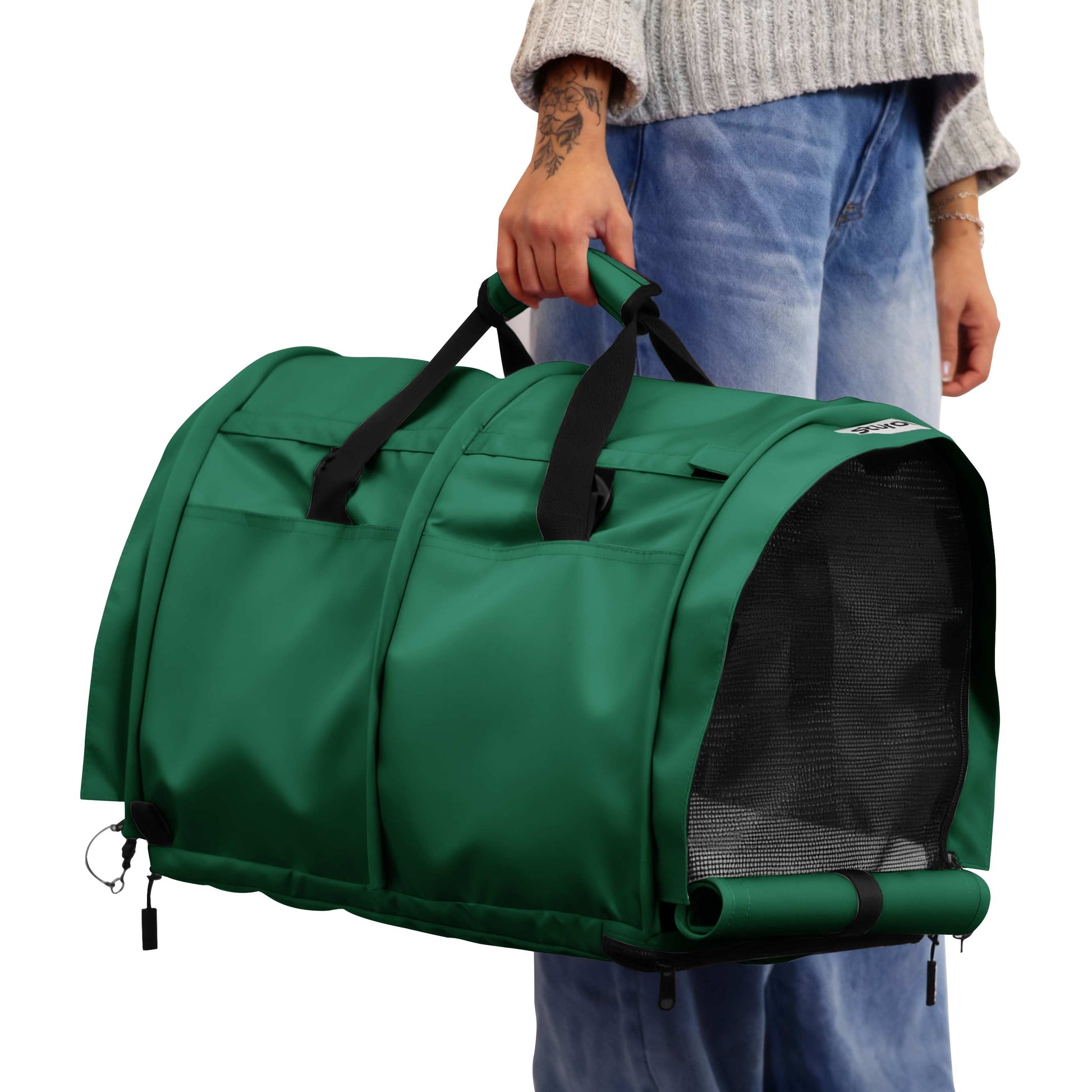 Person holding a green SturdiBag Pro 3.0 soft-sided pet carrier with mesh window and black handles.
