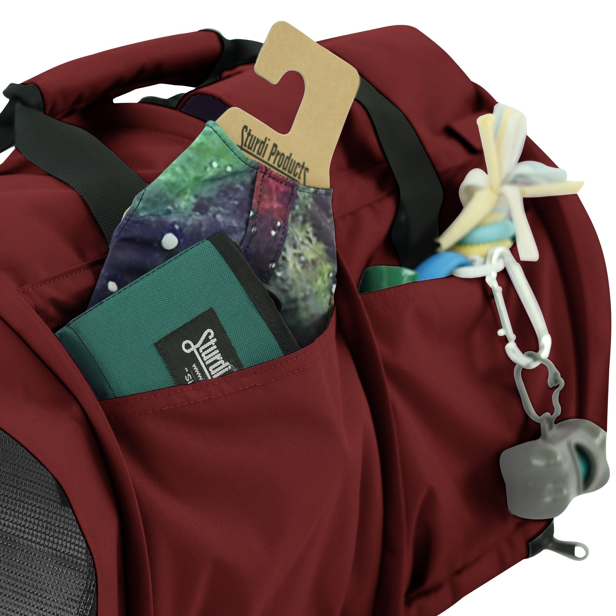 Close-up of a burgundy SturdiBag Pro 3.0 pet carrier with side pockets holding a wallet, mask, and pet toys.