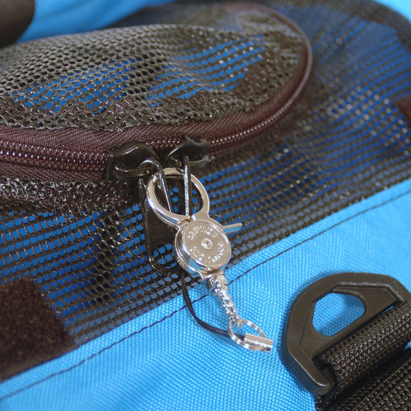 Silver metal zipper safety clip securing two black zipper pulls on a blue pet carrier with black mesh.