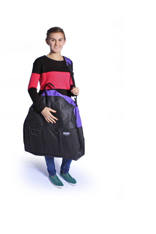 Woman holds a black and purple Sturdi Products carrying case for pop-up kennels, featuring a shoulder strap.