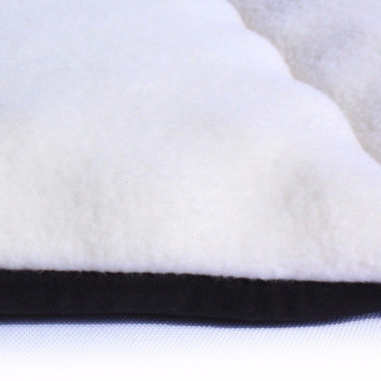Close-up of a white plush fleece pet carrier comfort pad with a black border.