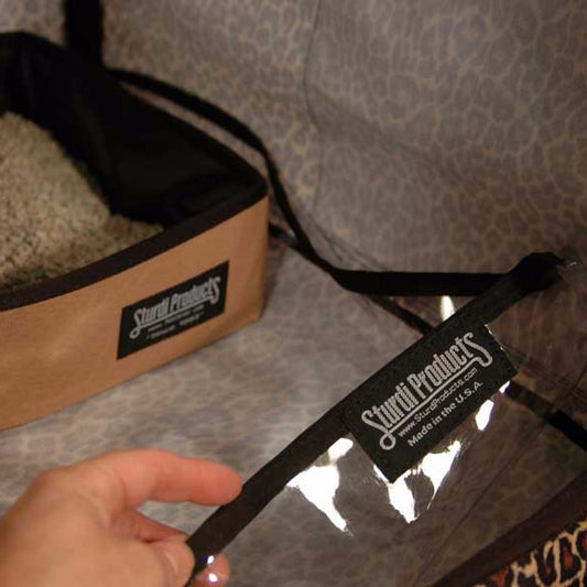 Clear vinyl liner with black trim and Sturdi Products label, held over a leopard print kennel floor.